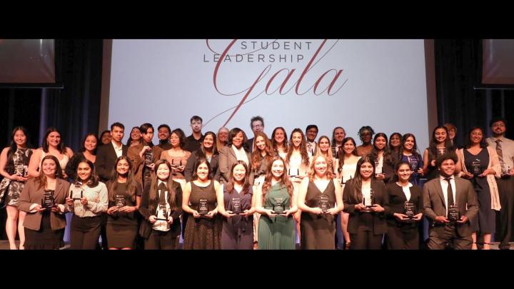 A large group of students standing on a stage holding awards