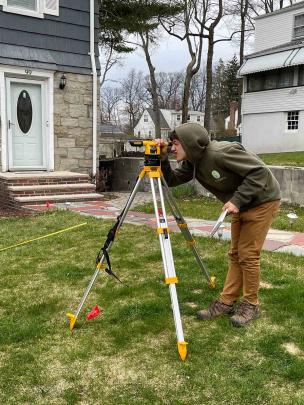 At a job site for his business New Gen Garden, Josh Kover cover seeks out the grade change for a retaining wall.