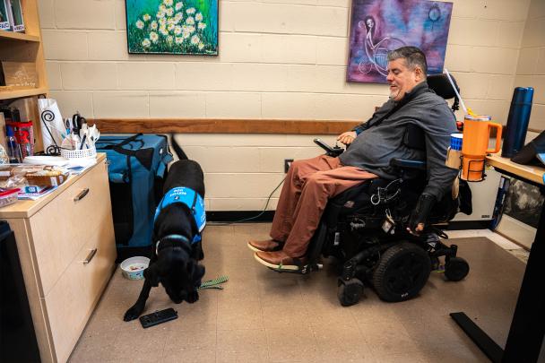 Javier Robles with is service dog who is picking up his cell phone