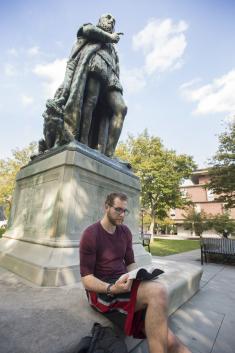 Connor Patriarca (SAS '23) sits and reads at the base of Willie the Silent on Voorhees Mall.